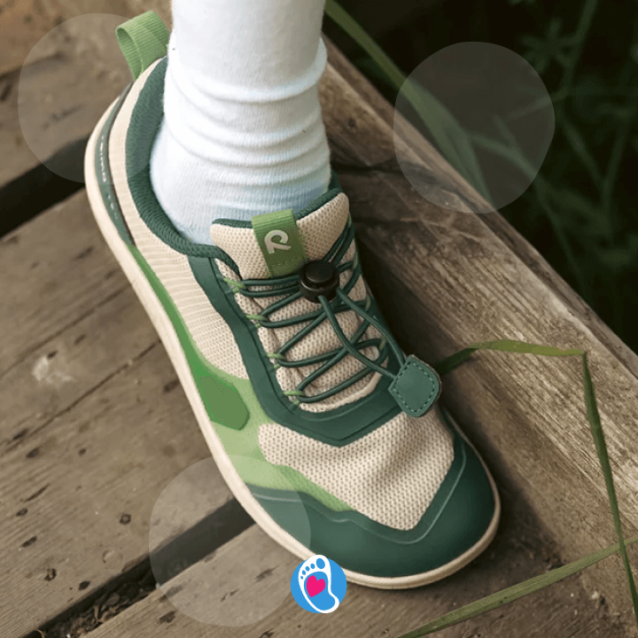 reimatec-tallustelu-buty-barefoot-buty-dla-dzieci-zero-drop-przyroda-podloga-Bosa-Stopka.jpg Zielone buty barefoot Reima dziecięce na drewnianym tarasie. Naturalny styl i zdrowy rozwój stopy.